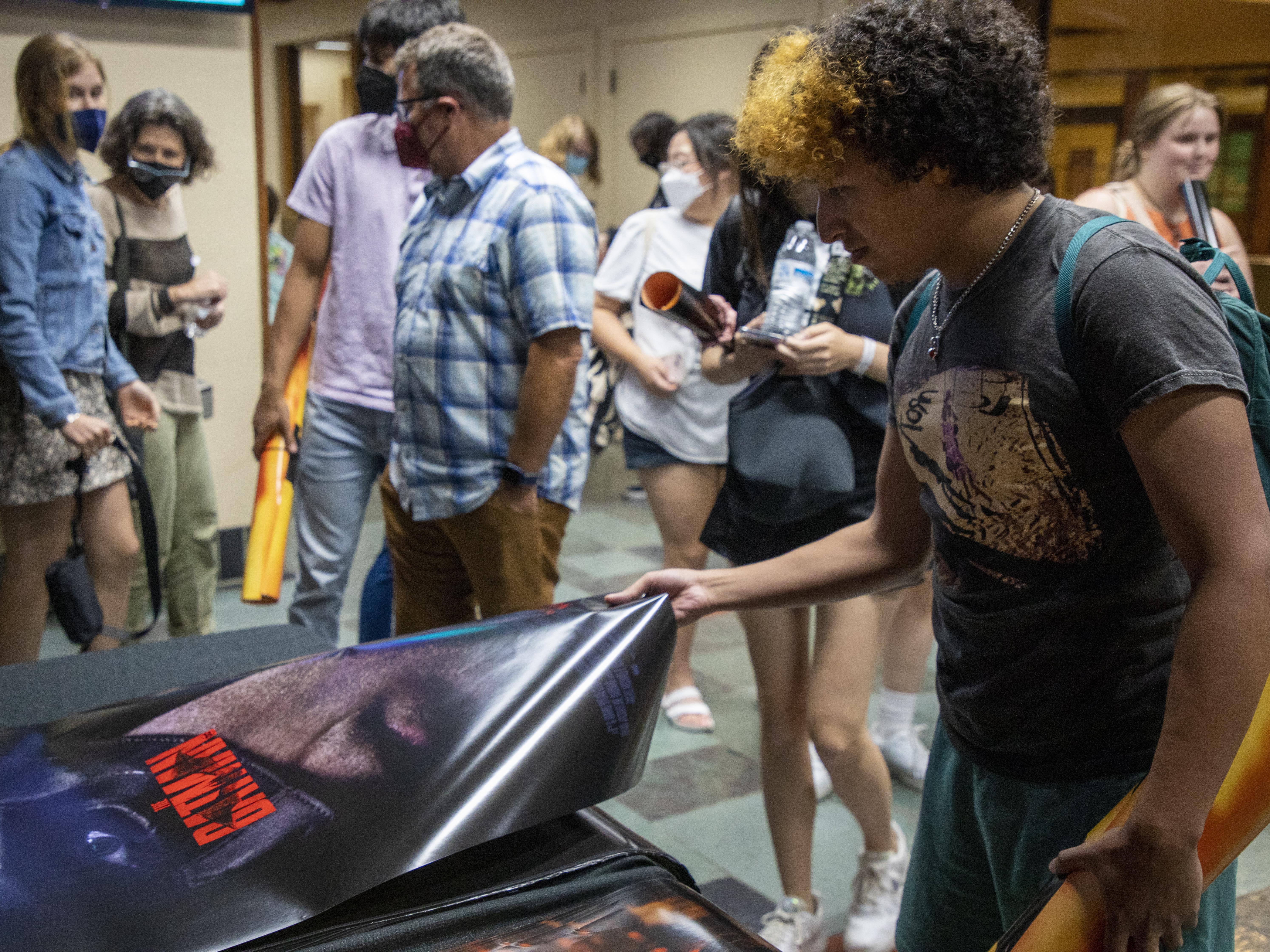 A student buys a poster at a special screening of The Batman.