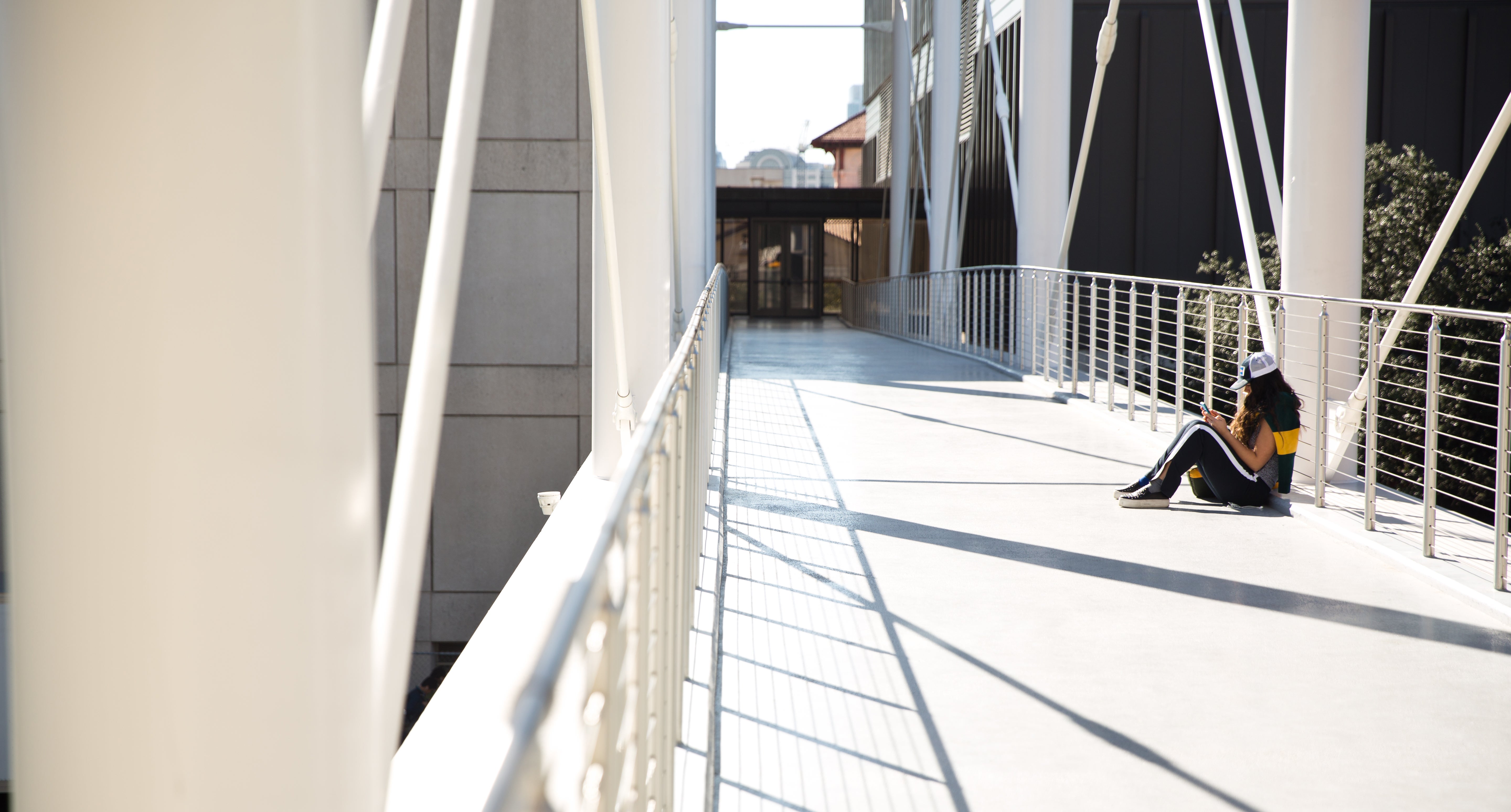 A student sits on the pedestrian bridge at Moody College of Communication.