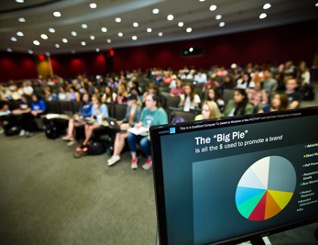 students sitting in a classroom with a powerpoint presentation on a computer screen in the forefront