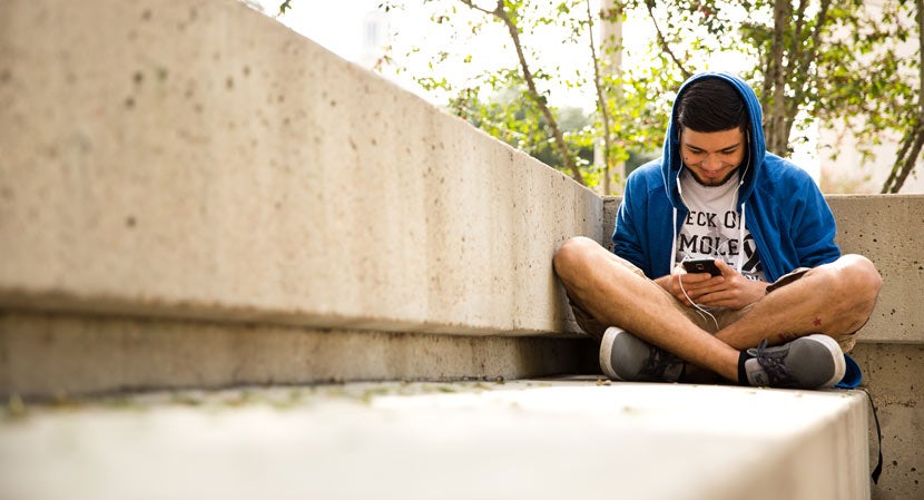 A student listens to a podcast on his phone.