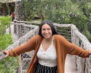 Larissa Aguilar outside smiling on a bridge with arms outstretched