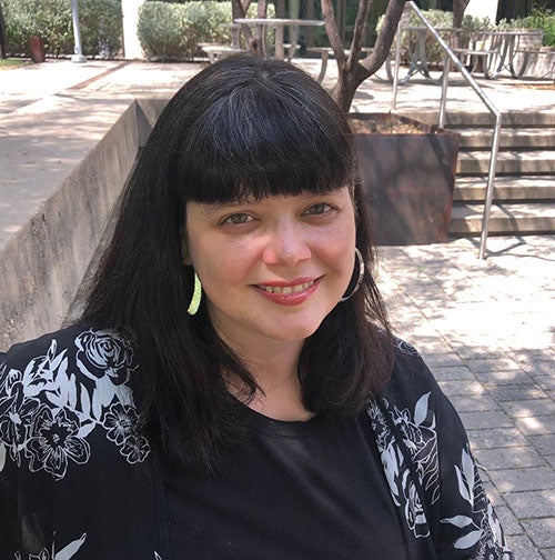 An older woman with dark hair and silver earrings