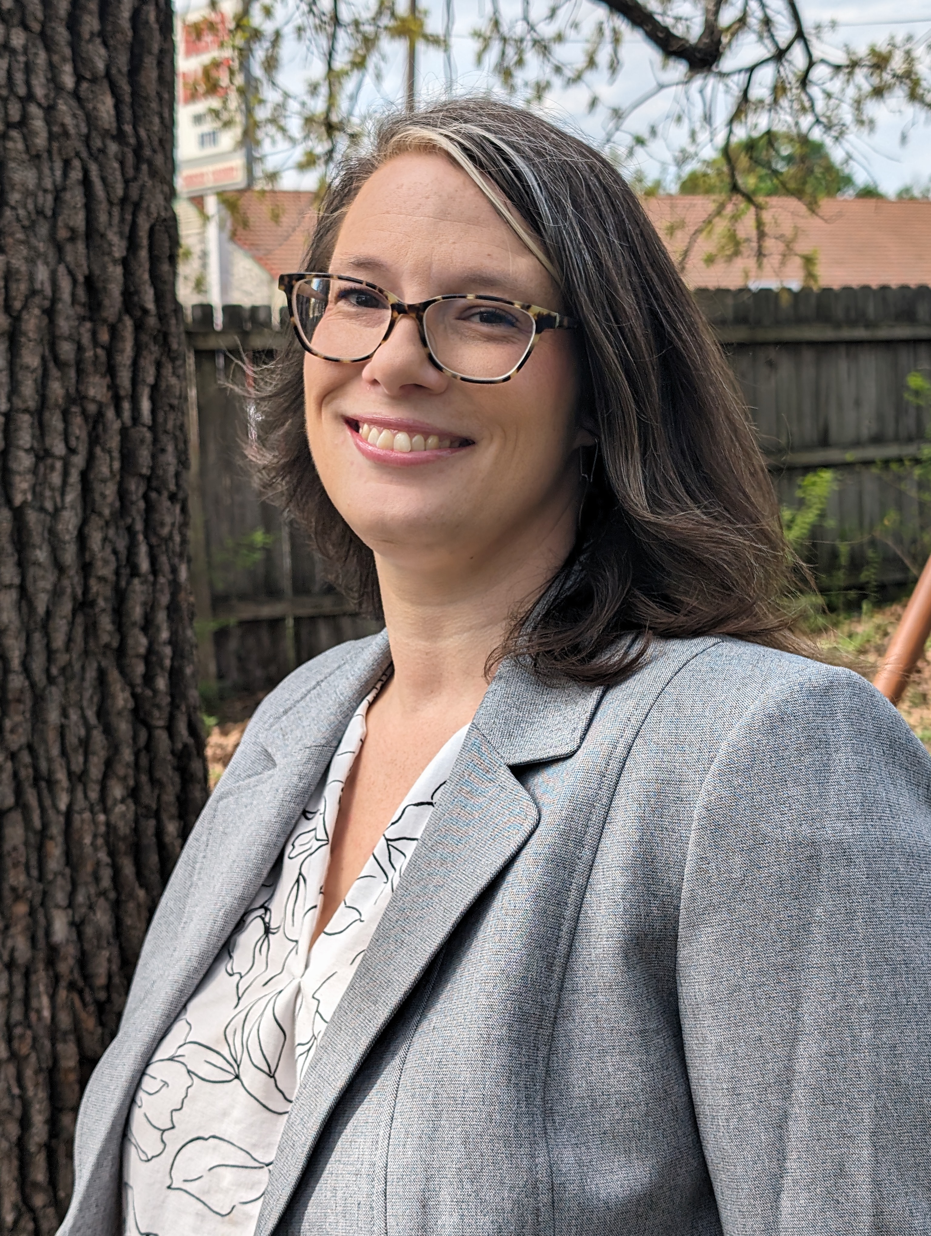 Headshot of the Center for Health Communication's Administrative Assistant Jen Graham, a 40-50 year-old white woman with shoulder-length brown hair wearing glasses and a gray blazer smiling at the camera.