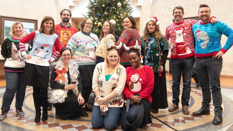 Faculty and staff group photo wearing holiday sweaters 