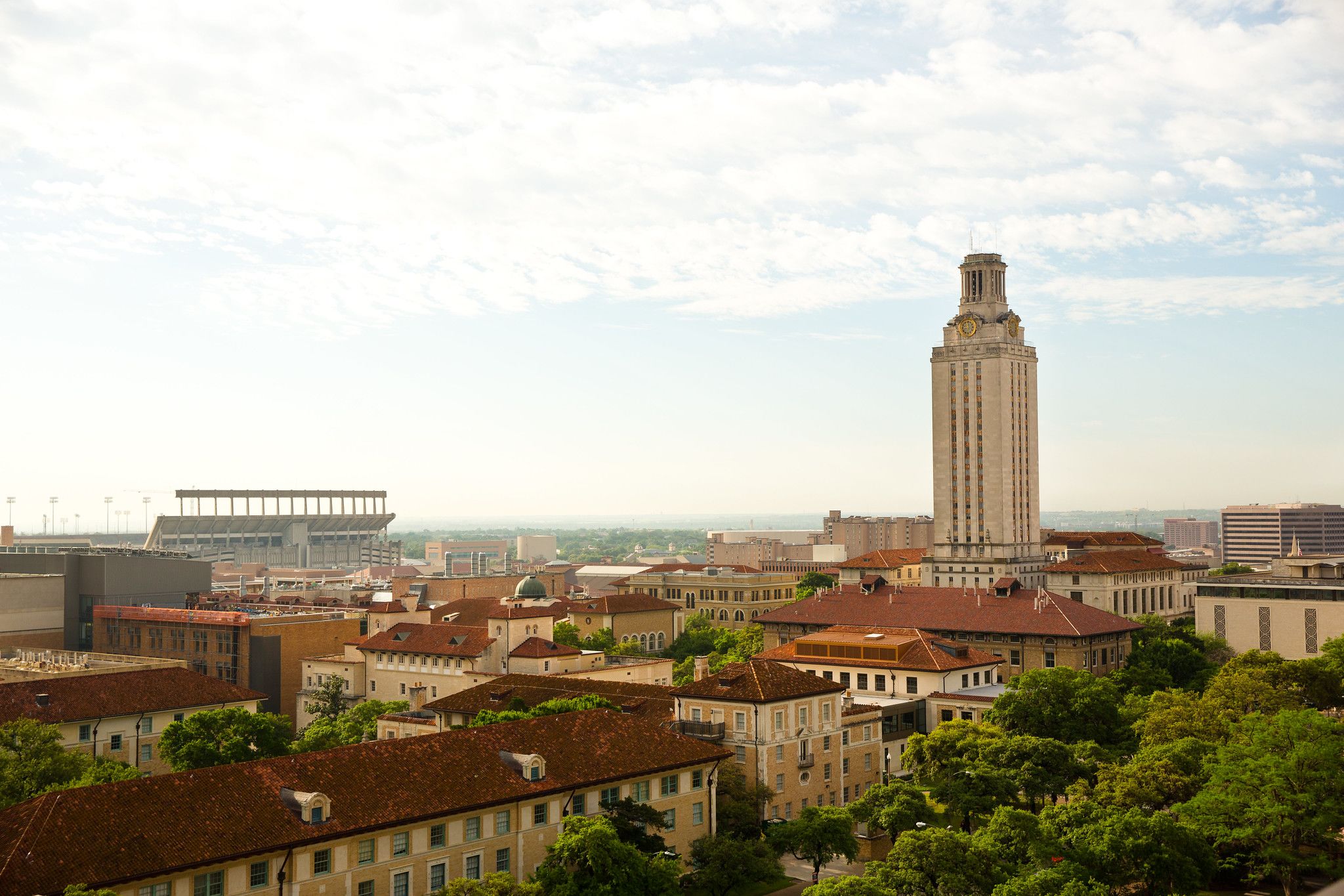 Photo of UT's campus of red tile rooved buildings in daylight under a mackerel sky, with the UT tower to the right. 