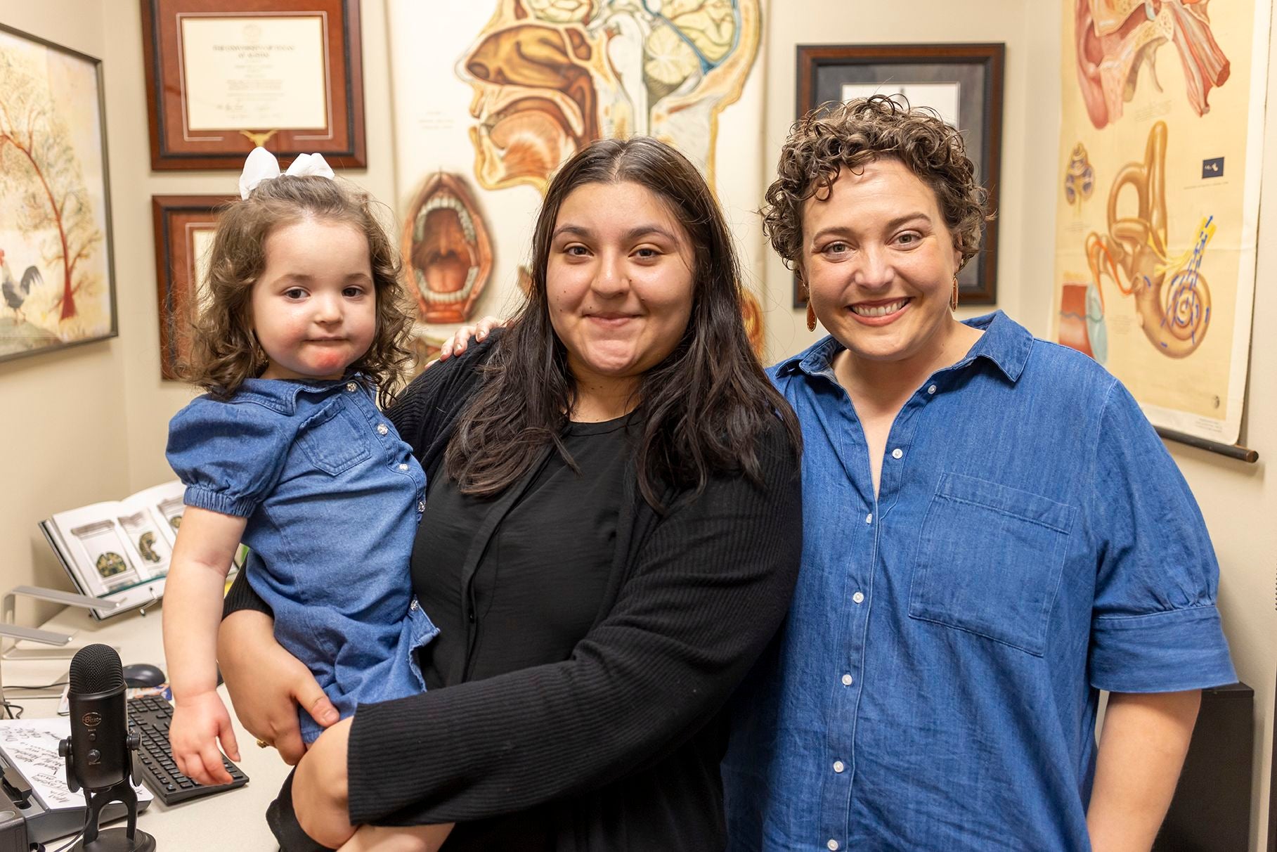 moody grad emily rangel with her daughter standing with professor dressed in blue and black