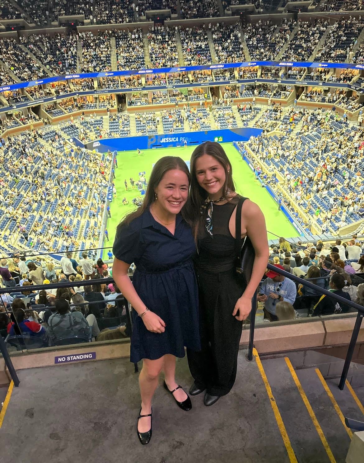 two UTNY alumni standing in front of soccer stadium smiling