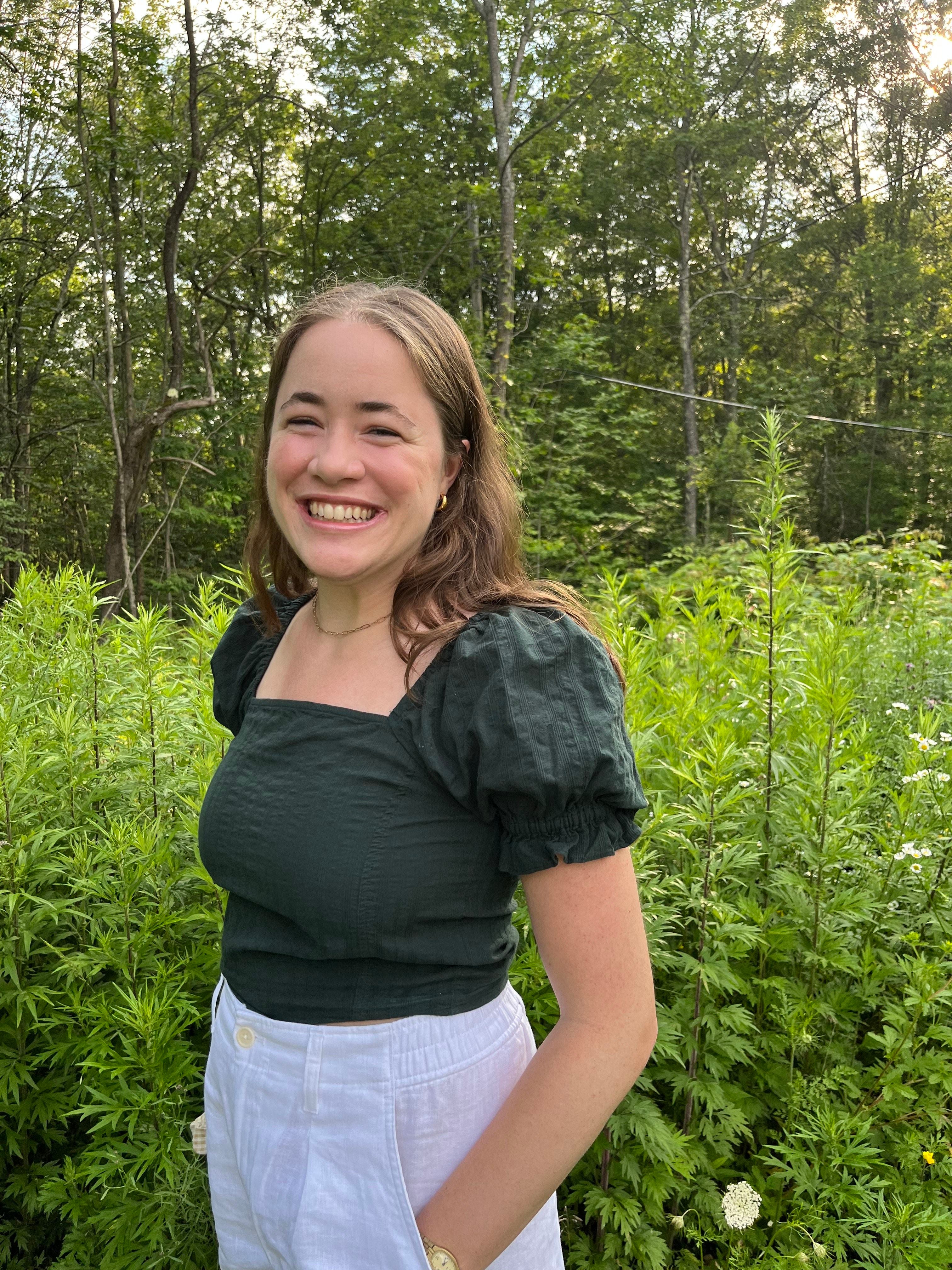 portrait of utny alum catherine harpold in front of green trees