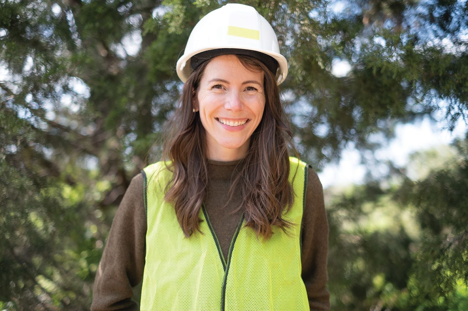 portrait of professor sam shorey in front of a tree with a hard hat on smiling