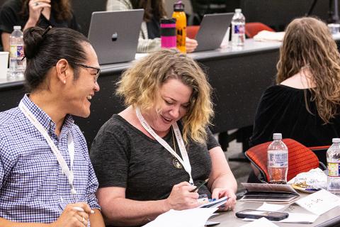 A white woman and an Asian man having a discussion in a lecture hall during the 2022 Health Communication Leadership Institute.