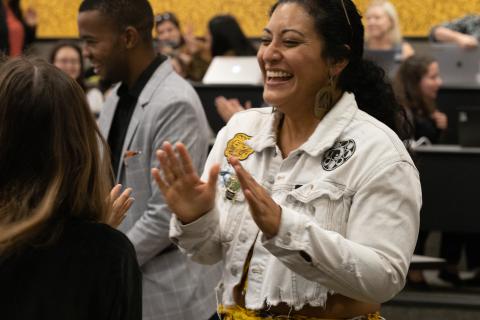 A Latina woman in a white denim jacket laughing