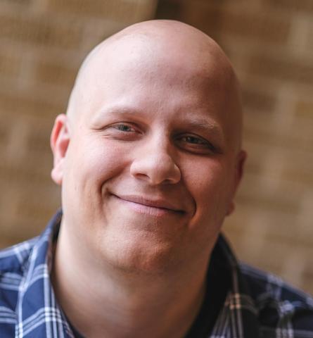 Headshot of Andy King, Ph.D., Associate Professor at the University of Utah. A white male, bald, wearing a plaid button down shirt smiling at the camera.