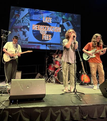4 members of student band Late Registration fees performing on stage