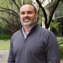 A man, Anthony Dudo, smiling for the camera in front of a tree.