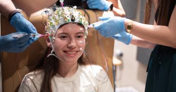 research patient wears cap to study eegs with hands putting gel on the cap