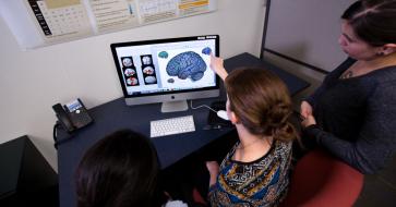 researchers around computer with brain image 