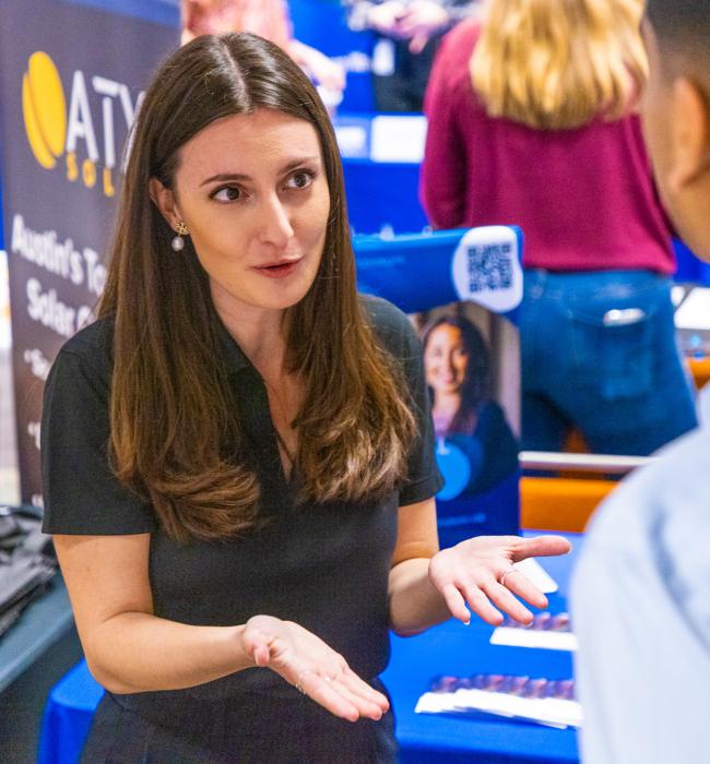 Recruiter speaks with student at a booth