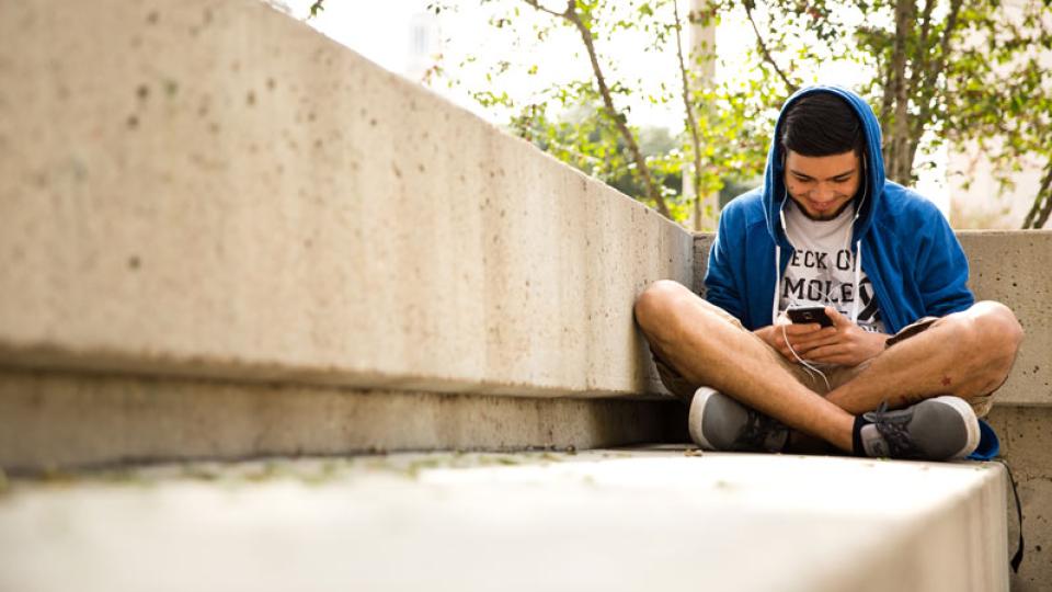 A student listens to a podcast on his phone.