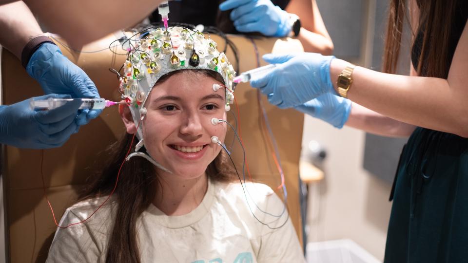 research patient wears cap to study eegs with hands putting gel on the cap