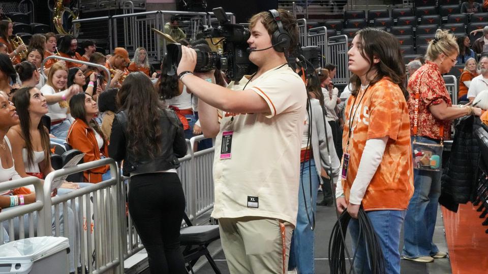 BVP student standing with a camera at a basketball at the moody center