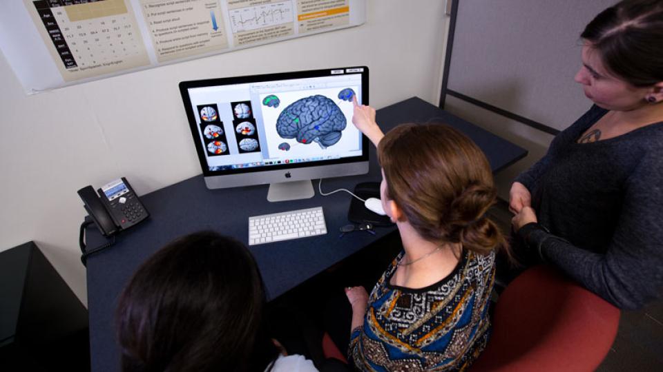 researchers around computer with brain image 
