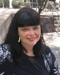 An older woman with dark hair and silver earrings