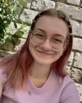 A young women with glasses and blonde hair with pink tips
