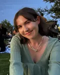 A young woman with shoulder length brown hair and a green dress