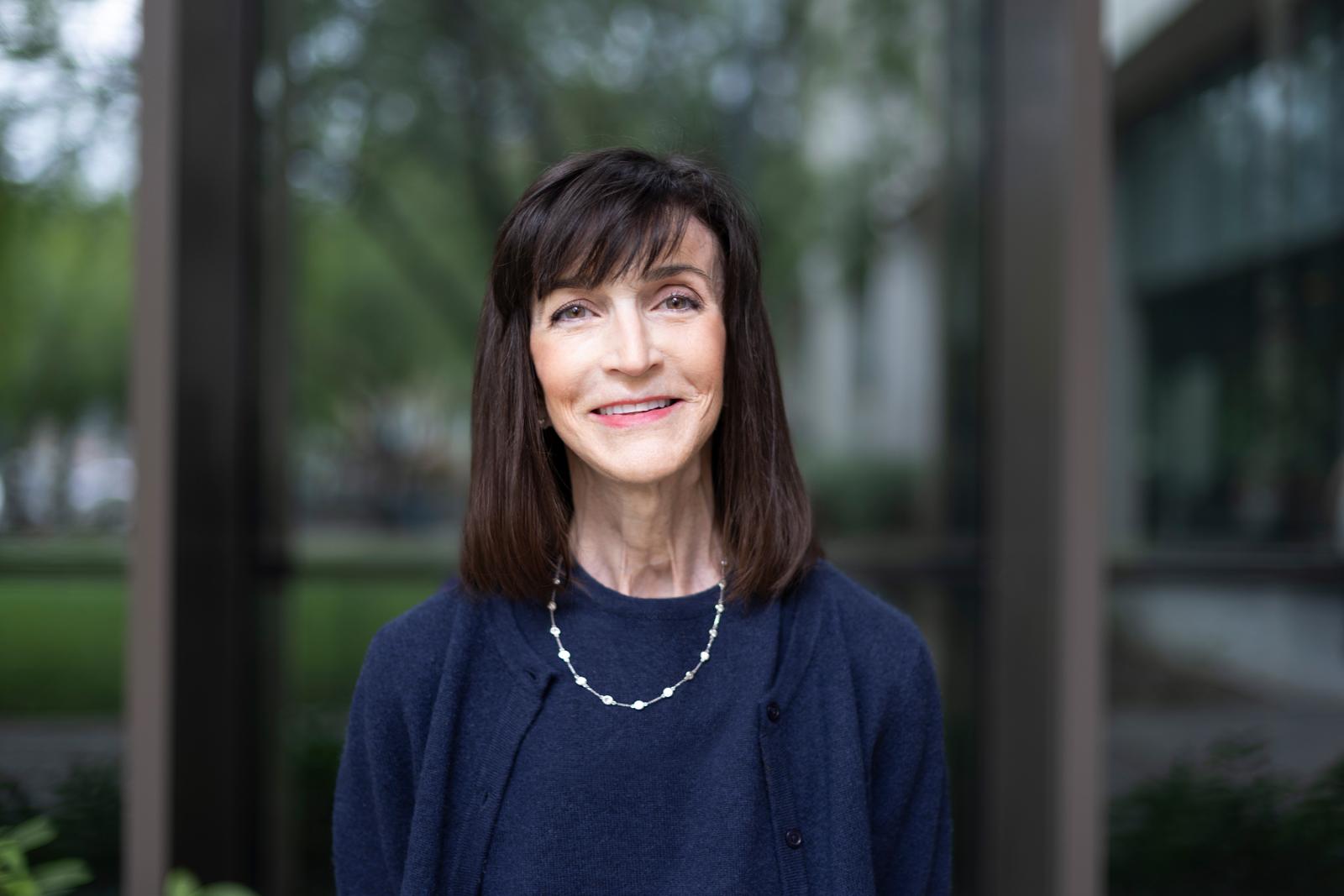 Interim dean anita vangelisti stands in front of moody college wearing a blue outfit 