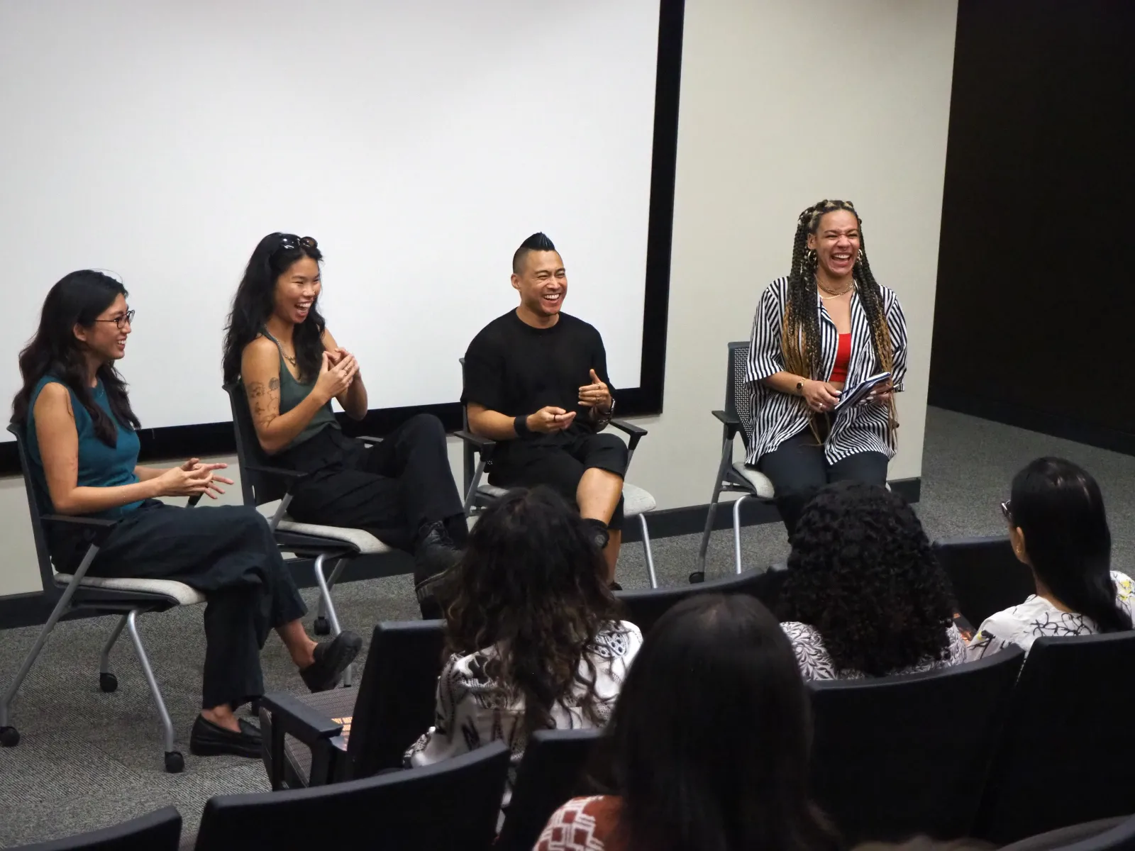 Professor PJ Raval speaks on a panel with three other professionals and this photo depicts all of them laughing together in an audiorium