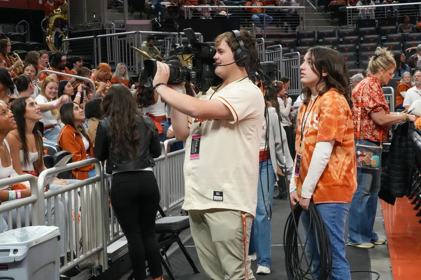 BVP student standing with a camera at a basketball at the moody center