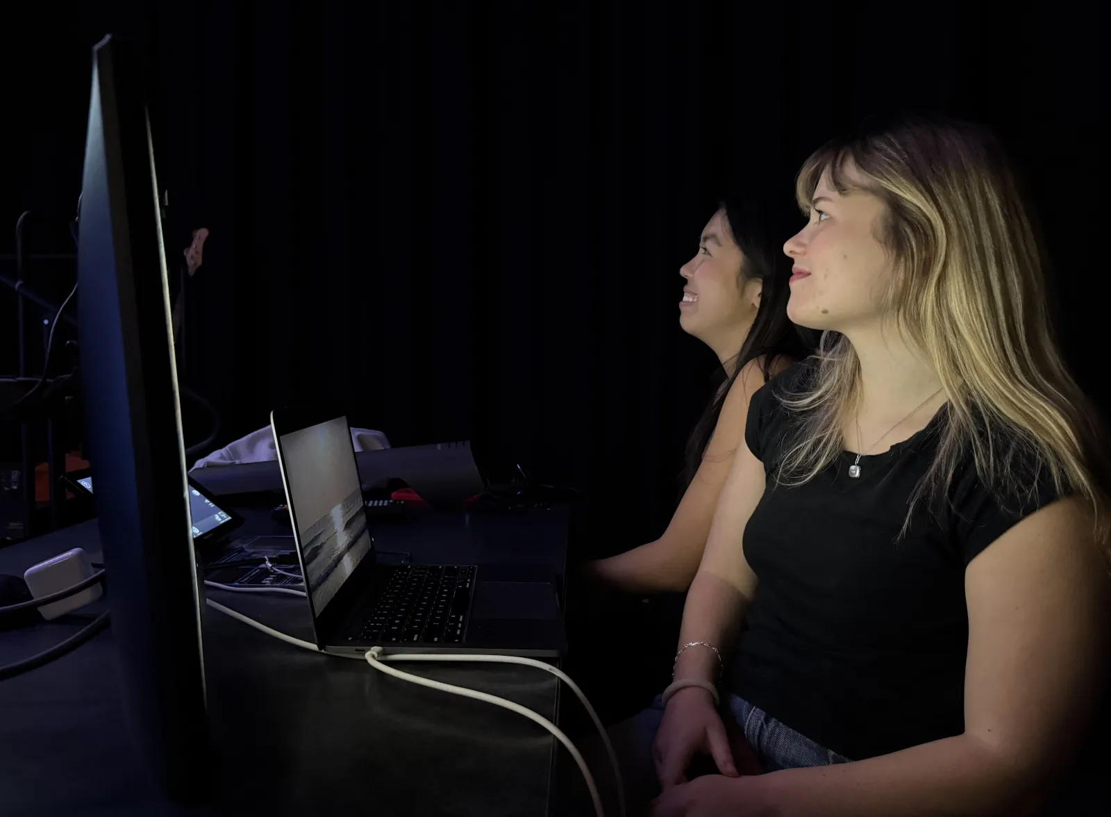 2 students monitoring sound, lights, and graphics smile during the Red River Reverb performances