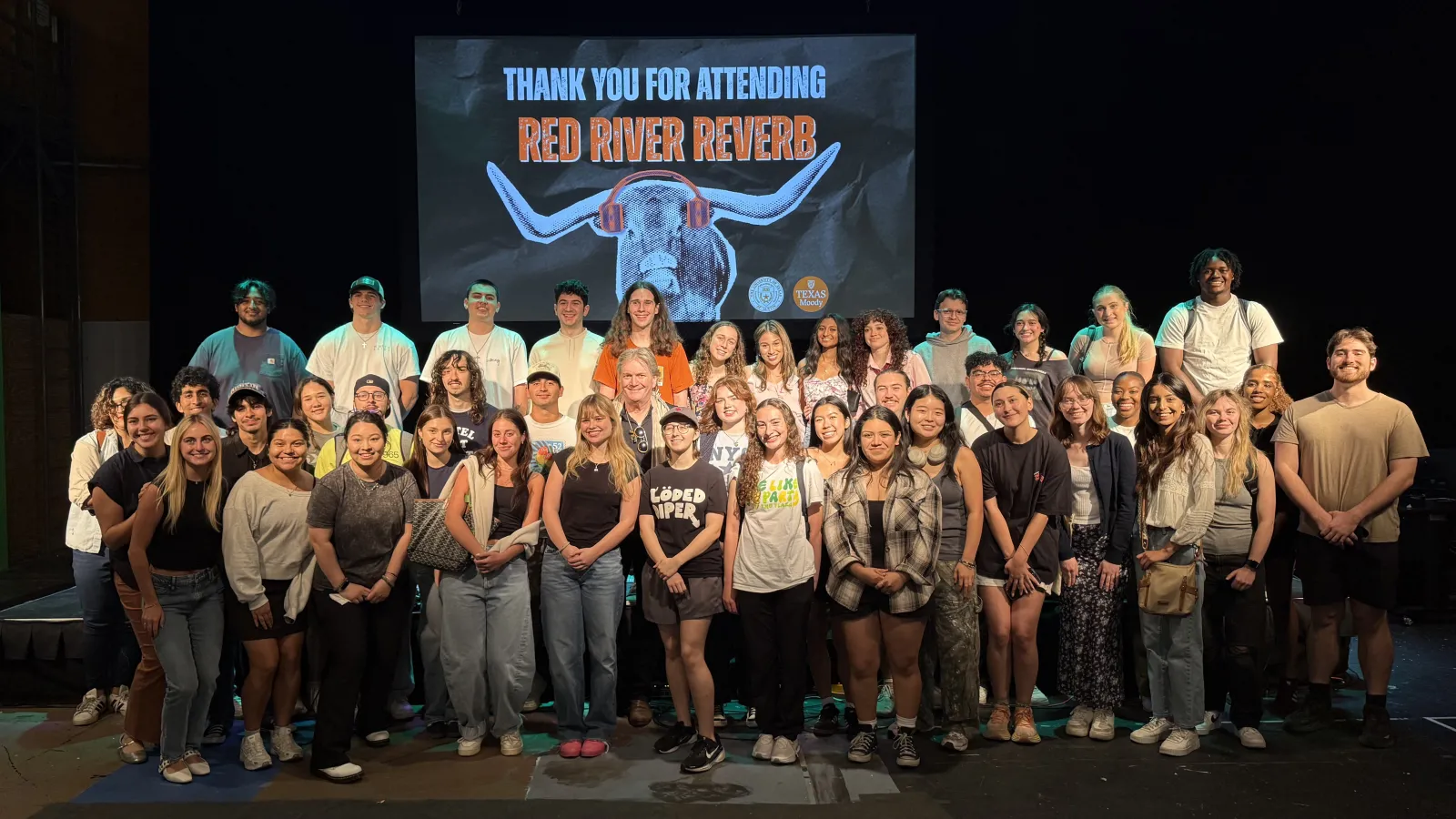 The full class of students smiling for a group photo in front of the Red River Reverb stage set