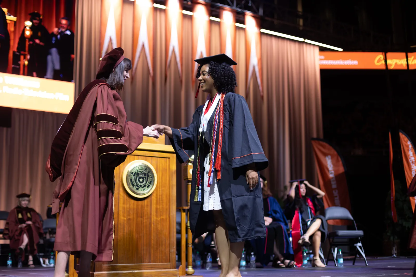 campbell williams shaking dean vangelisti's hand during Moody College's graduation ceremony