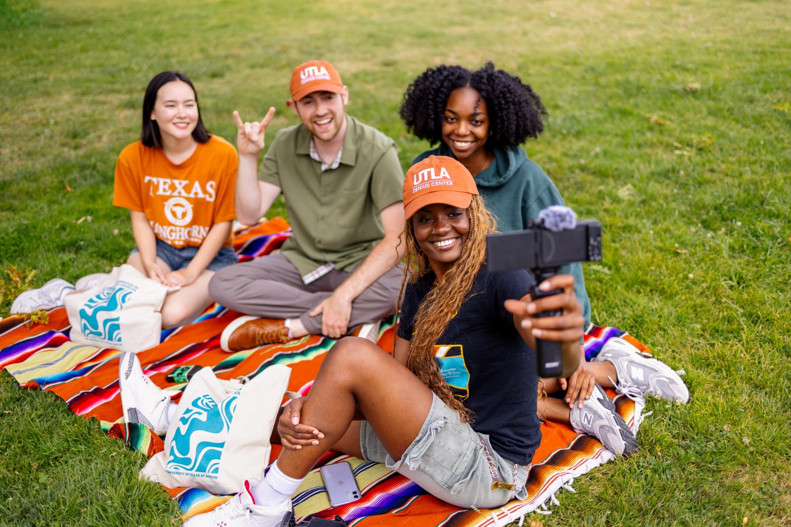 Students on a picnic blanket wearing UTLA hats