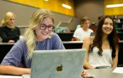 classroom shot with young female students smiling in the foreground