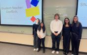 Five students standing in front of their presentation and smiling