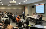 Image depicts a panel speaker presenting to a class.