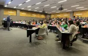 Professor Quigley addresses a large lecture hall of students.
