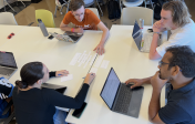 faculty and students sitting at a table working collaboratively. 