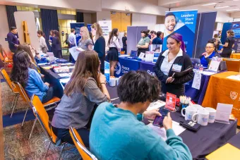 Students sit at recruiter booths and interact with companies