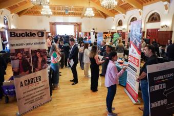 Lines of booths in a ballroom with students talking to companies