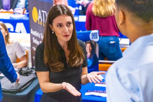 Recruiter speaks with student at a booth
