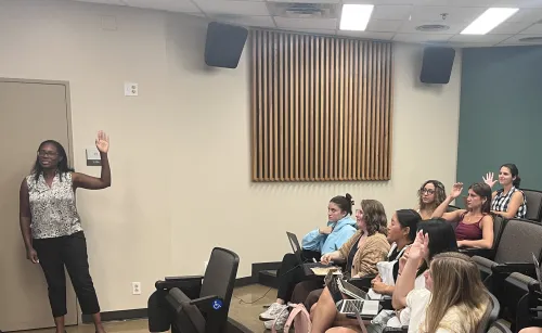This image depicts a faculty member and students raising their hands. 