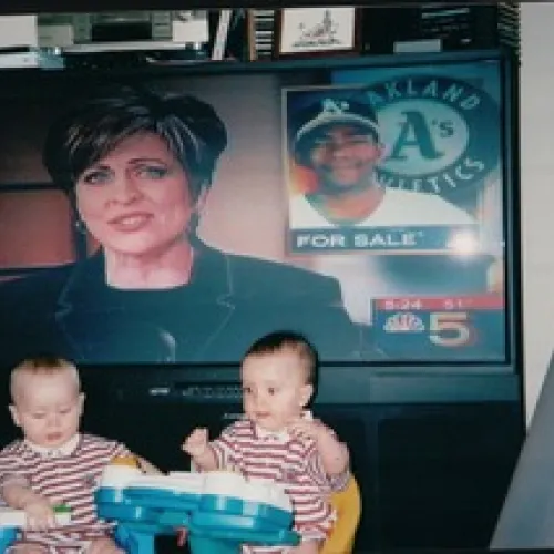 Two brothers watch their mom on TV.