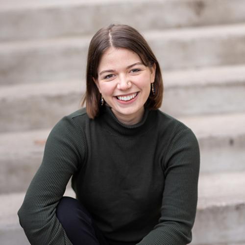 A young woman in a black shirt sitting on steps