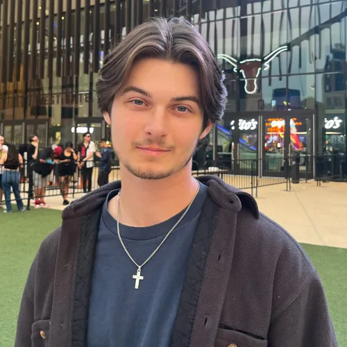 A young man standing in front of UT's Moody Center