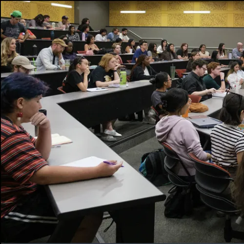 Students sitting at desks in a classroom, yellow walls