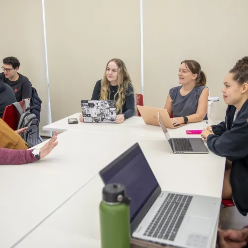 Photo of professor and students talking around table