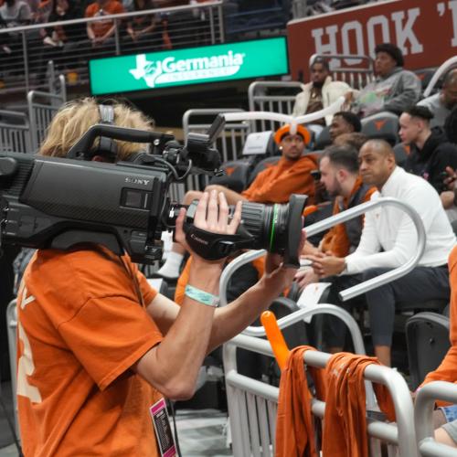 student filming at basketball game